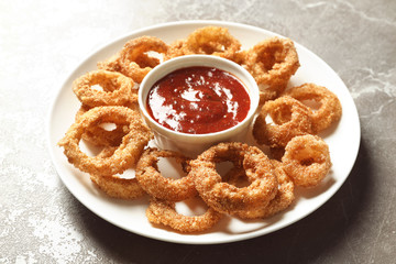 Homemade crunchy fried onion rings with sauce on color table