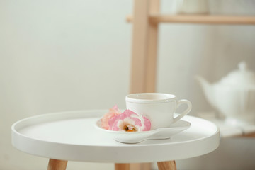 Cup of tea, saucer and flowers on table indoors