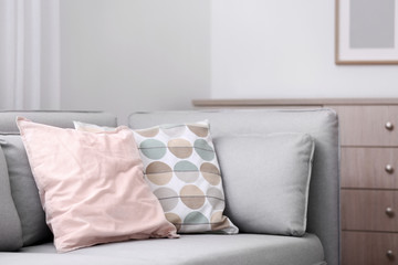 Different soft pillows on sofa in room. Interior element