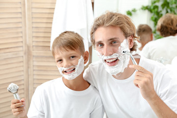 Father and son shaving together in bathroom