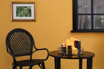 Room interior with armchair and burning candles on table