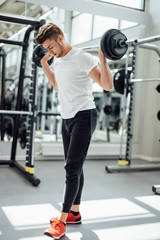 Fototapeta na wymiar Fit muscular caucasian crossfit man exercising with dumbbell in fitness hall with a lot of mashines.