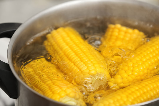 Stewpot with boiling water and corn cobs, closeup