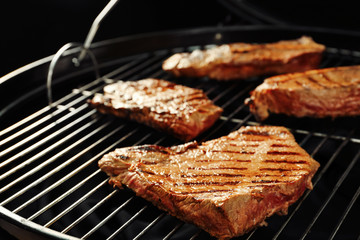 Fresh grilled tasty meat steaks on barbecue grate