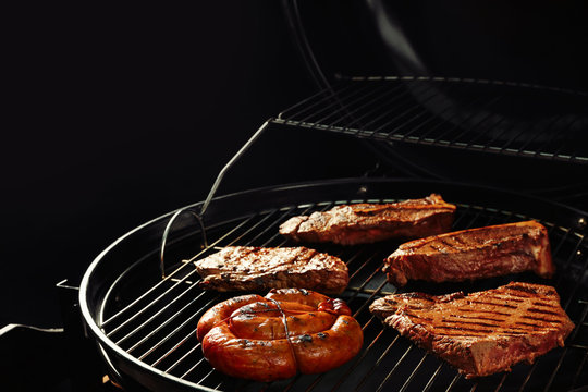 Fresh grilled tasty meat steaks and sausage on barbecue grate