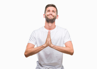 Young handsome man over isolated background begging and praying with hands together with hope...