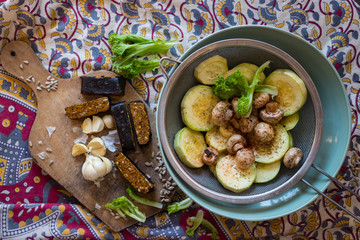 Woman hands holds steamed, cooked, baked and roasted organic assorted vegetables with paprika, herbs, oregano in sieve. Zucchini, mushrooms. Vegan lunch, vegetarian dinner, healthy food