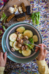 Woman hands prick on fork steamed, cooked, baked and roasted organic assorted vegetables with paprika, herbs, oregano. Zucchini, mushrooms. Vegan lunch, vegetarian dinner, healthy food