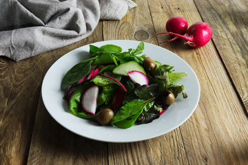 Freshly prepared salad made of greens, red radishes and green olives