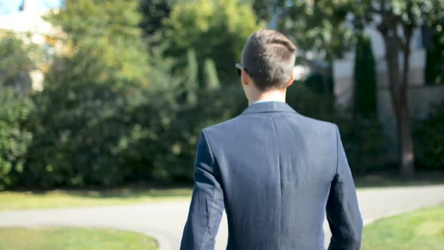 Young businessman walking forward in a hurry to job interview or meeting, back to camera