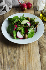 Freshly prepared salad made of greens, red radishes and green olives