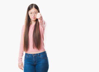 Young Chinese woman over isolated background wearing glasses looking unhappy and angry showing rejection and negative with thumbs down gesture. Bad expression.