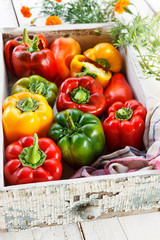 Beautiful juicy bell peppers in a white wooden box. Organic vegetables. White wooden table in the garden. Style rustic. Colorful
