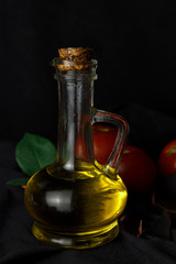Obraz na płótnie Canvas A bottle of olive oil on a black background. The dark still life. Close-up