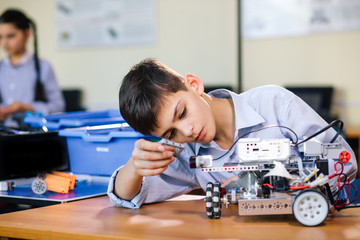 Little boy in robotics school makes robot managed from the constructor, child learns robot constructing. - obrazy, fototapety, plakaty