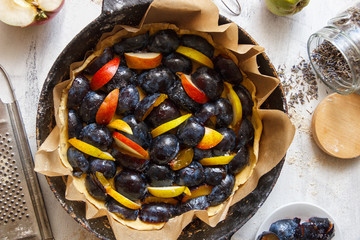 Preparation of plum fruit pie. Working process. Light wooden background