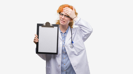 Young redhead doctor woman holding clipboard stressed with hand on head, shocked with shame and surprise face, angry and frustrated. Fear and upset for mistake.