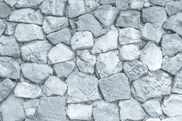 Seamless white pattern of decorative grey slate stone wall surface of modern style design decorative uneven cracked realmasonry wall of multicolored stones or blocks with cement or sandstone.
