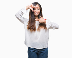 Young asian woman over isolated background smiling making frame with hands and fingers with happy face. Creativity and photography concept.