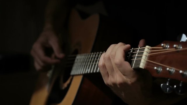 Close up shot of guitarist's hands plays chords on acoustic guitar