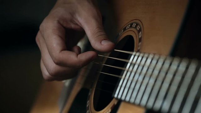 Close up shot of guitarist's hands plays chords on acoustic guitar