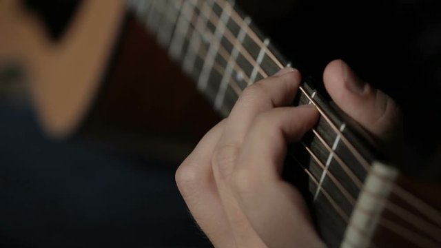 Close up shot of guitarist's hands plays chords on acoustic guitar