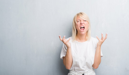 Adult caucasian woman over grunge grey wall celebrating mad and crazy for success with arms raised...