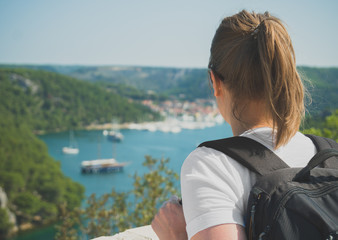 Fototapeta premium Female tourist with backpack looking at city near the lake.