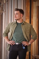 Young strong man watching possing on outdoors structure background.European stile.