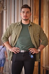 Young strong man watching possing on outdoors structure background.European stile.