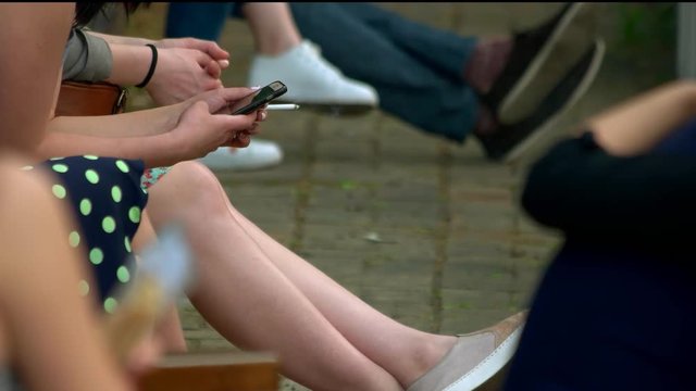 Woman smoking and using smartphone. Close up. Teenagers hanging out.