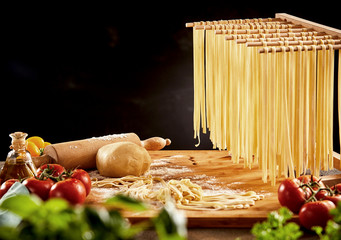 Noodles hanging on wooden rack over cutting board