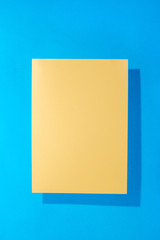 Sheet of yellow paper on a blue background for decoration, for text design, for a template
