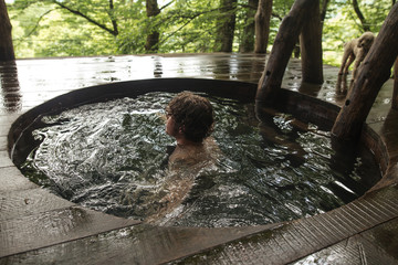 back view photo. man is standing in the cold water in wooden bath. close up shot