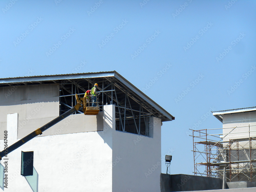 Wall mural construction workers standing in the mobile crane bucket while working at high level in the construc