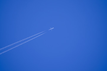 Against the background of a blue clear sky, an airplane leaving an inverse trail