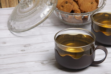 cup of green tea on table and a bowl of choco chips cookies