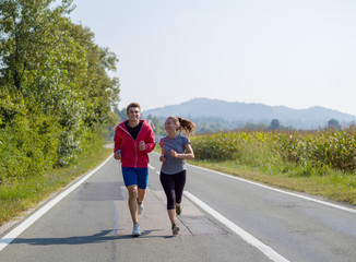 young couple jogging along a country road