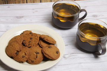 cup of green tea on table and a bowl of choco chips cookies