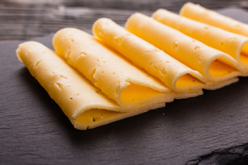 Piece and slices of cheese on a wooden background