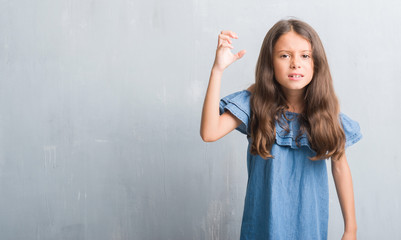 Young hispanic kid over grunge grey wall angry and mad raising fist frustrated and furious while shouting with anger. Rage and aggressive concept.