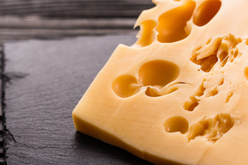 Piece and slices of cheese on a wooden background