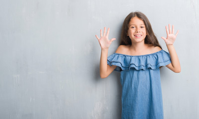 Young hispanic kid over grunge grey wall showing and pointing up with fingers number ten while...