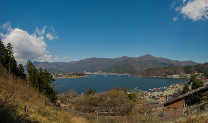 Fototapeta na wymiar View from above of Kawaguchi lake located near Fuji mountain and surrounded by mountains, with buildings and hotels on the shore