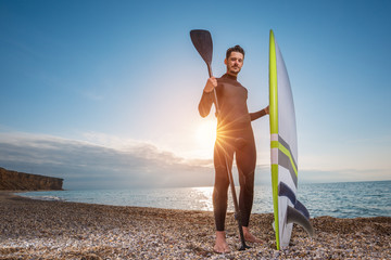 Portrait of a young male surfer in a wetsuit on the beach.