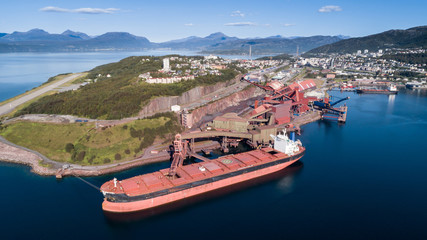 Aerial shot of a cargo ship anchoring in  port terminal and loading iron ore, Narvik, Norway