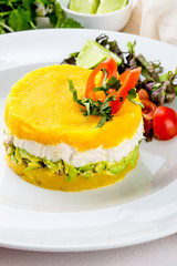PERUVIAN FOOD. Causa rellena de pollo. Chicken causa rellena. Traditional peruvian dish from yellow potato, chicken, avocado on white plate