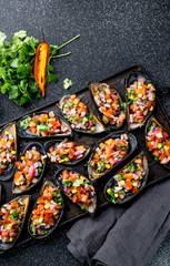 PERUVIAN FOOD. Choros a la chalaca. Big mussels, choros zapatos seasoned with purple onion, tomatoes, corn and lemon. Top view, black background. Traditional peruvian dish