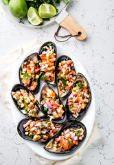 PERUVIAN FOOD. Choros a la chalaca. Big mussels, choros zapatos seasoned with purple onion, tomatoes, corn and lemon. Top view, white background. Traditional peruvian dish