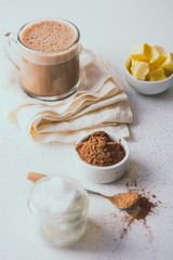 BULLETPROOF CACAO. Ketogenic keto diet hot drink. Cacao blended with coconut oil and butter. Cup of bulletproof cacao and ingredients on white background